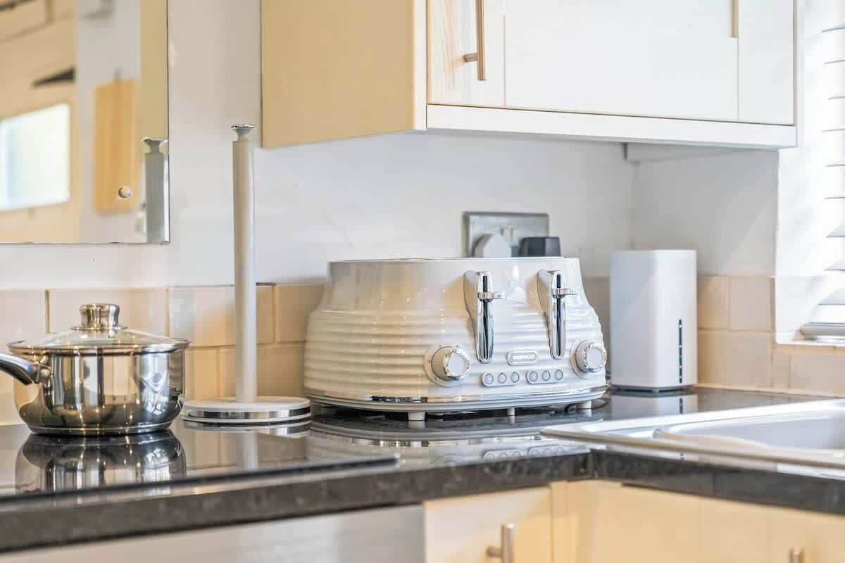 A kitchen with a stainless steel pot, a white electric kettle, and a white coffee maker on the counter.
