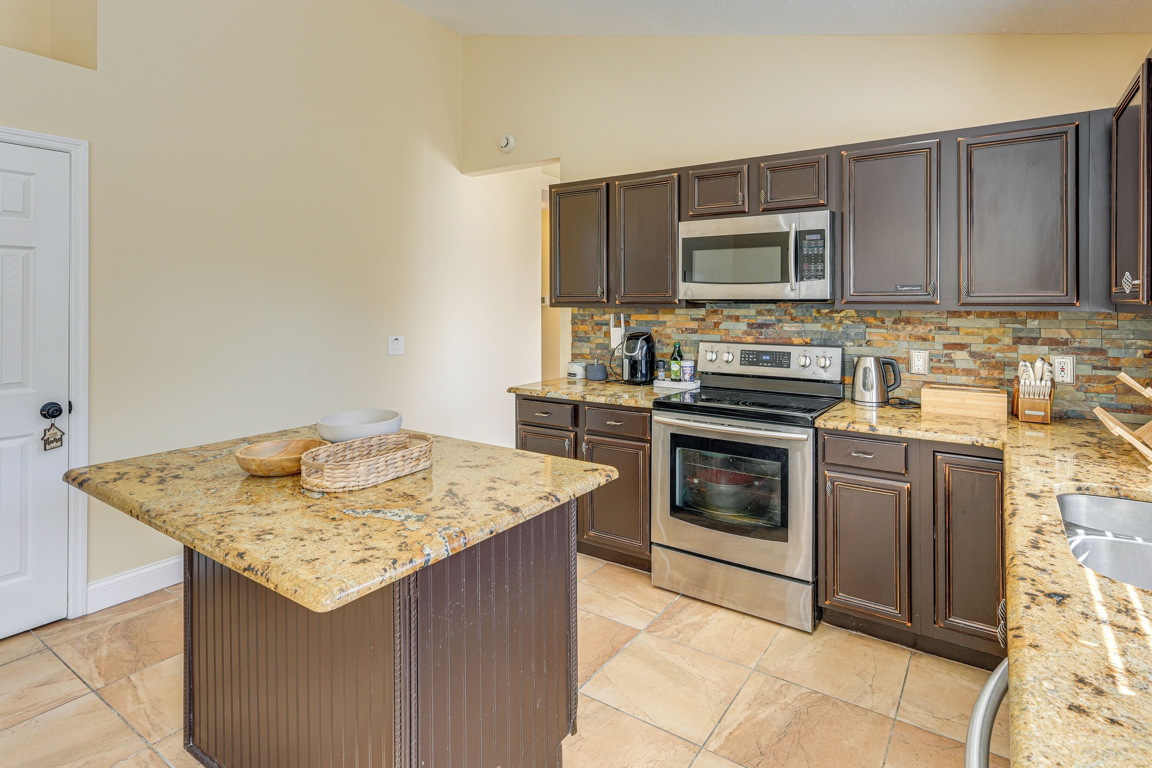 A kitchen with granite countertops, stainless steel appliances, and dark wooden cabinets.