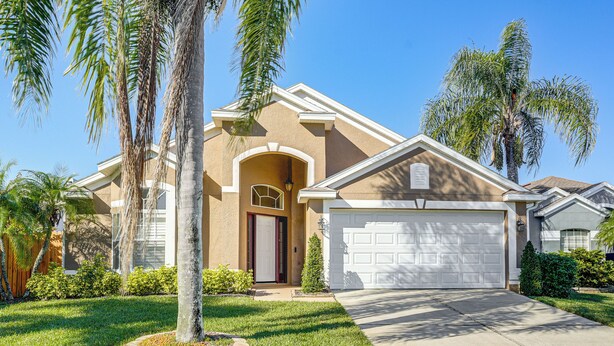 A residential house with a front garage, a well-maintained lawn, and palm trees. - Apopka Family Home w/ Yard, 13 Mi to Dtwn Orlando (Apopka)