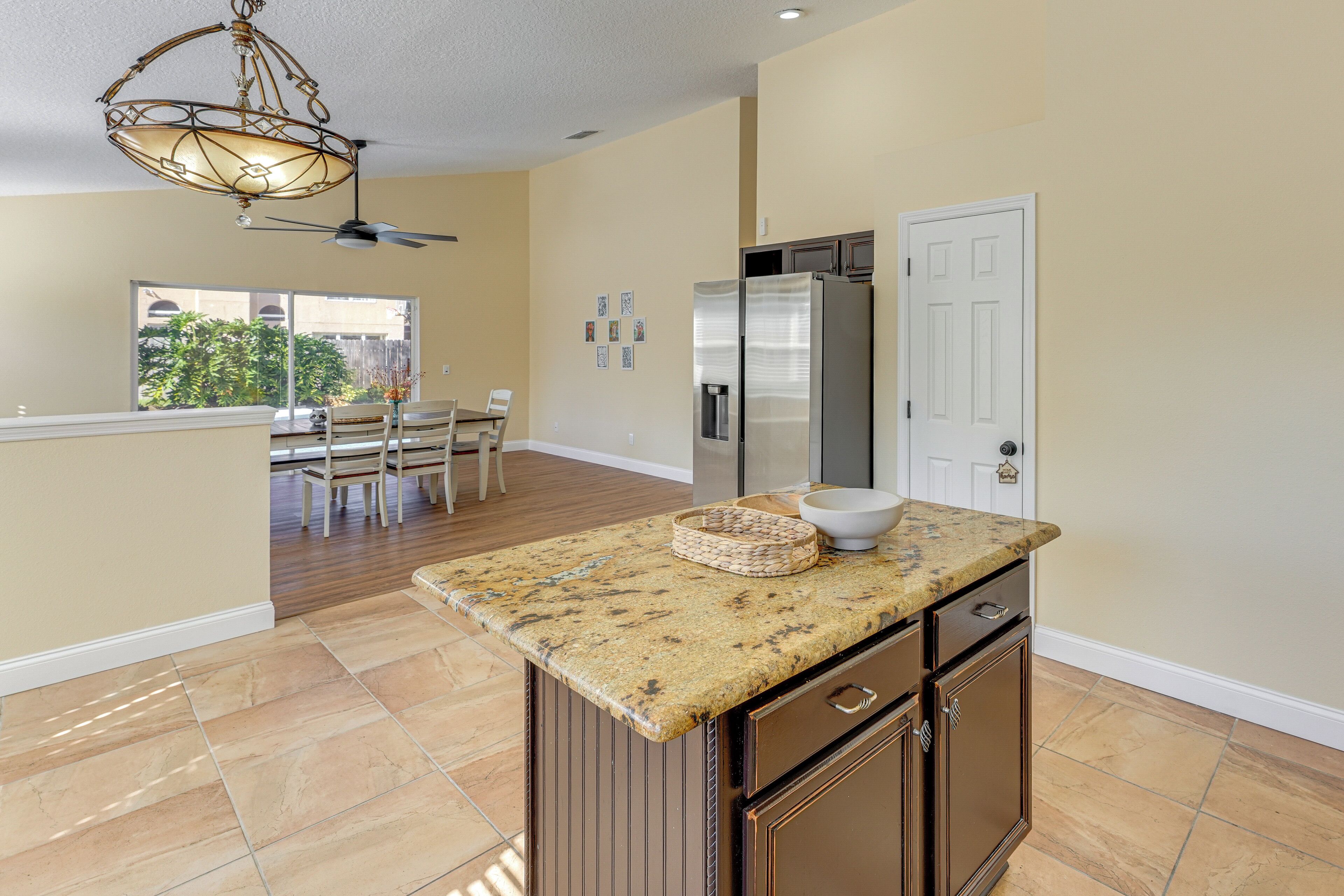 A kitchen with a granite countertop, a refrigerator, and a dining area with a table and chairs.