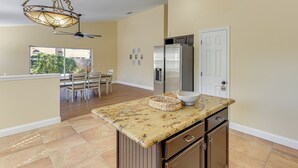 A kitchen with a granite countertop, a refrigerator, and a dining area with a table and chairs. - Apopka Family Home w/ Yard, 13 Mi to Dtwn Orlando (Apopka)