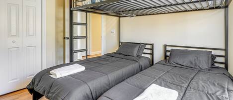 Habitación con dos camas, una litera arriba y una puerta blanca.