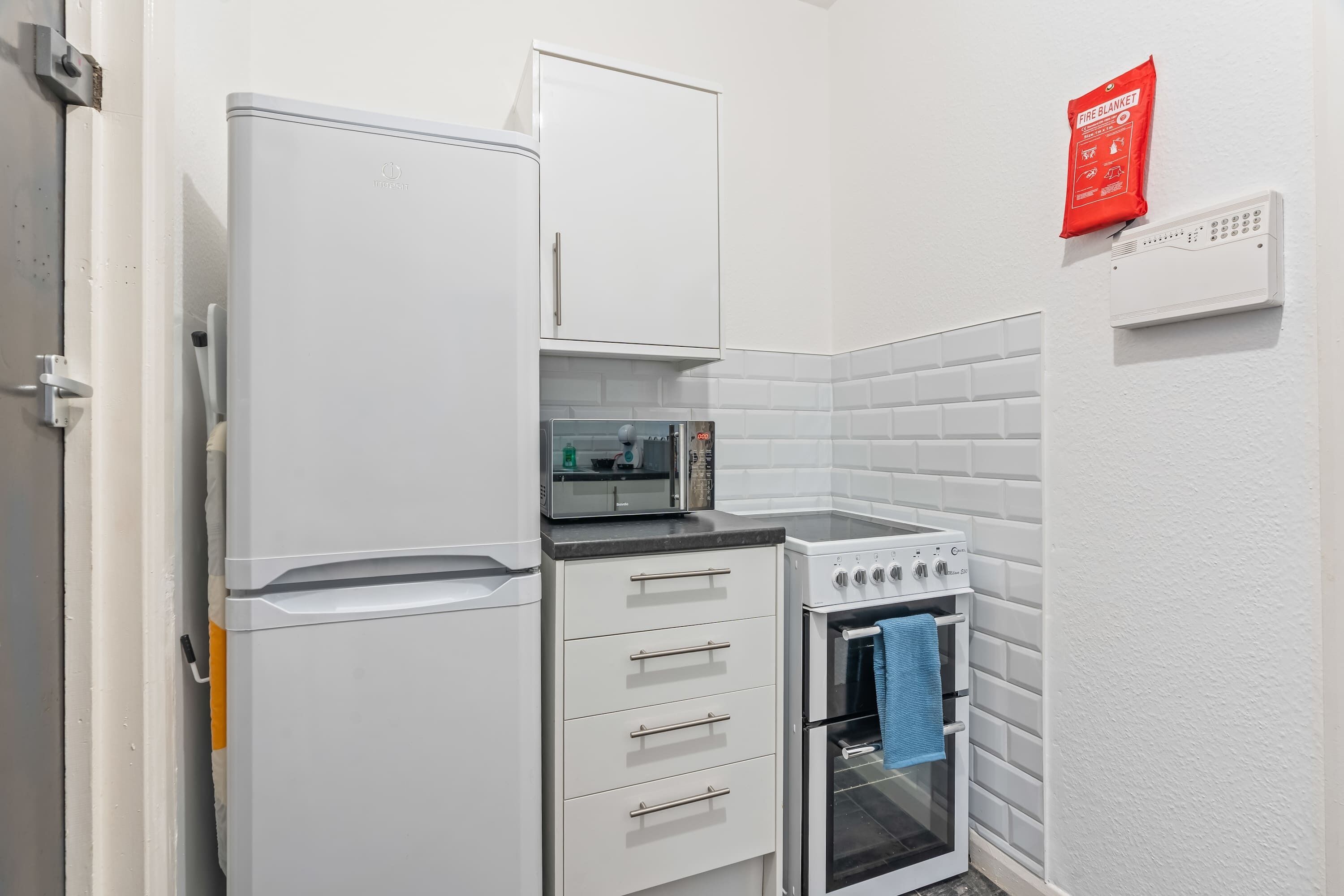 A compact kitchen with a refrigerator, oven, and microwave.