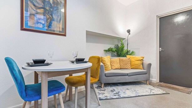 Un comedor con una mesa redonda, dos sillas, un sofá y una puerta.