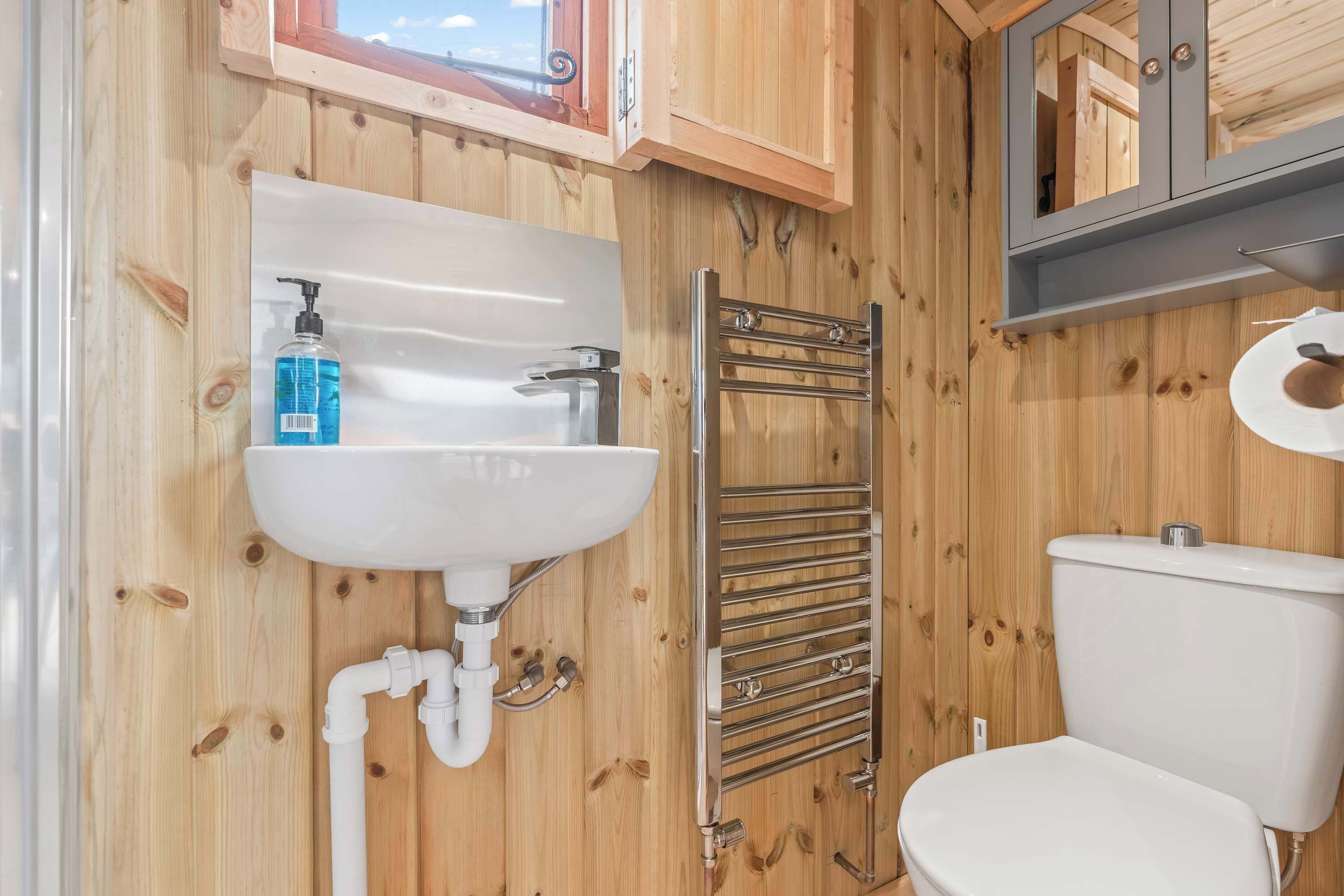 A wooden-paneled bathroom with a white sink, a towel rack, and a toilet.