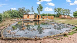 Un chalet rustique doté d’une terrasse en bois et d’un petit étang.