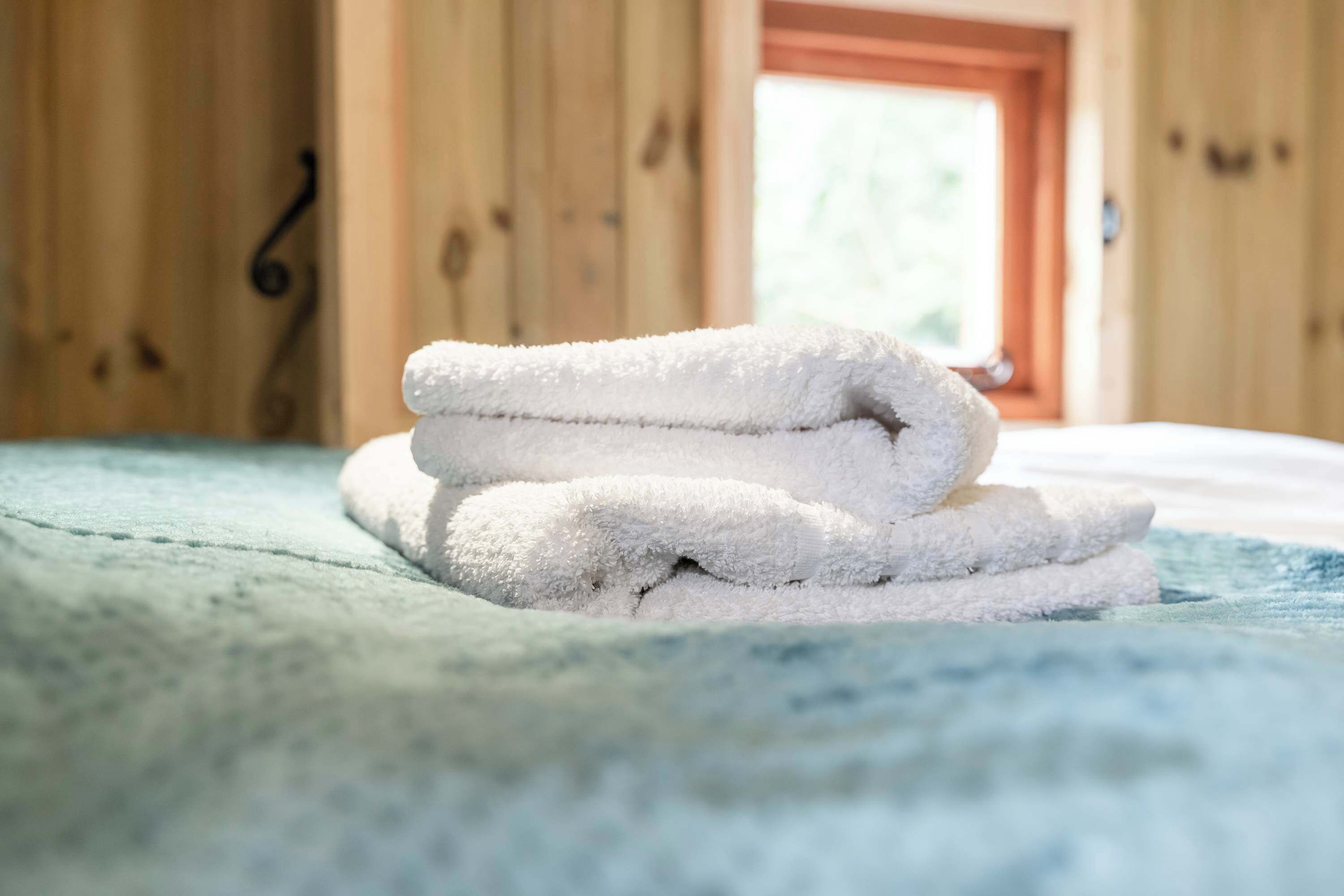 Un montón de toallas blancas sobre una cama con una colcha azul.