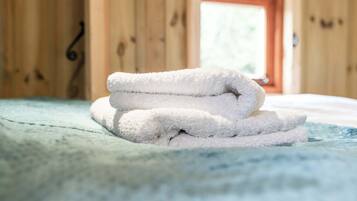 Un montón de toallas blancas sobre una cama con una colcha azul.