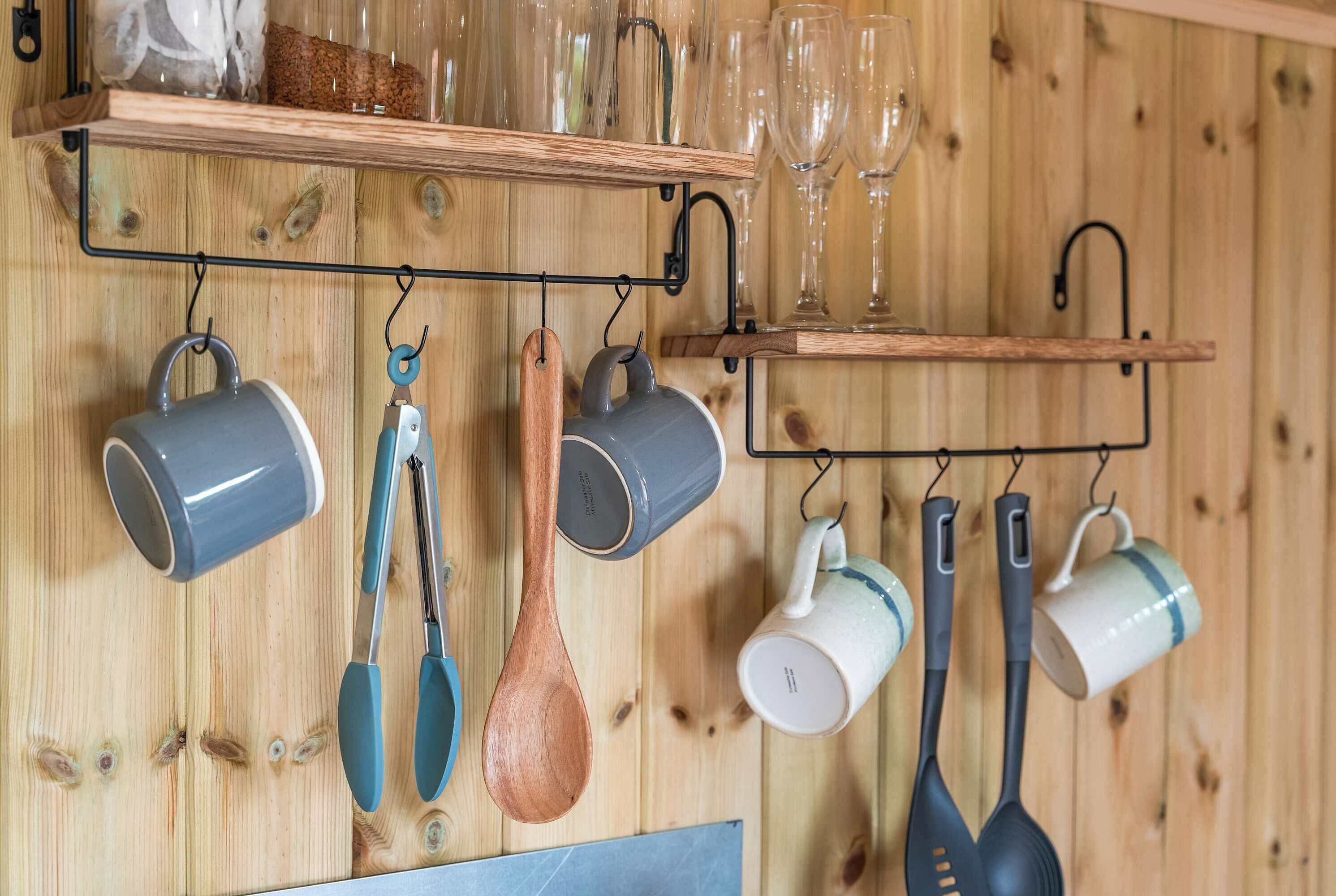 Una cucina con pareti in legno, utensili pensili e un ripiano con bicchieri da vino.