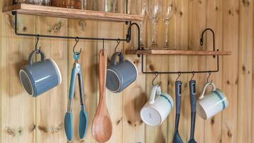 Una cucina con pareti in legno, utensili pensili e un ripiano con bicchieri da vino.
