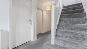 A staircase with a carpeted landing and a white door at the top. - 4-Bed Beeston Getaway | Free Parking (Beeston)