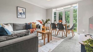 A modern living room with a grey sofa, a coffee table, and a dining area with a table and chairs. - 4-Bed Beeston Getaway | Free Parking (Beeston)