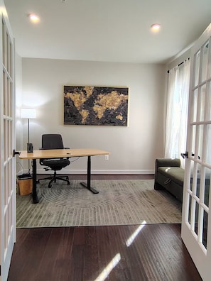 A modern office space with a wooden desk, black office chair, and a large abstract painting on the wall. - Family-Friendly Home in Quiet Neighborhood in Frederick, MD (Frederick)
