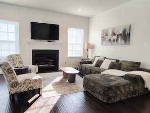A living room with a fireplace, a television, and a painting on the wall. - Family-Friendly Home in Quiet Neighborhood in Frederick, MD (Frederick)