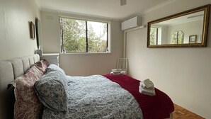 A bedroom with a bed, a ceiling fan, a window, and a mirror.