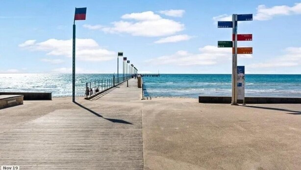 A wooden pier extending into the sea with a clear sky.