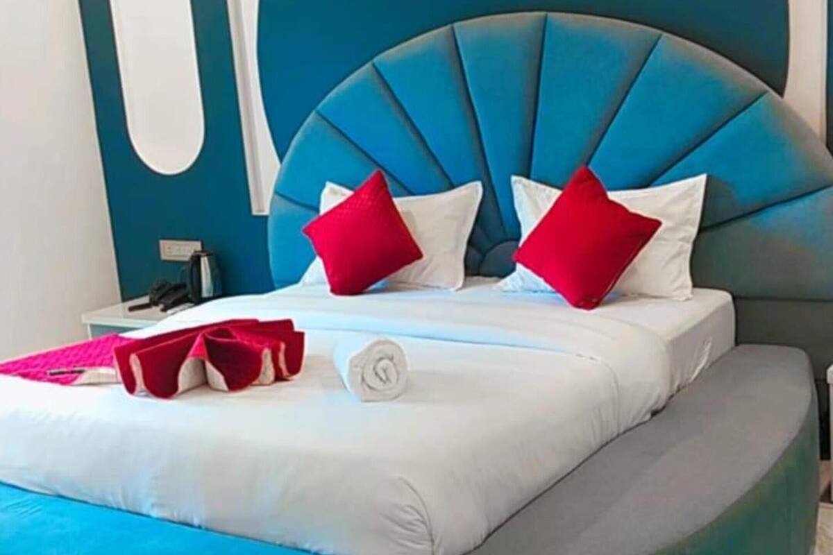 A modern bedroom with a circular bed, blue and white bedding, and a unique headboard design.