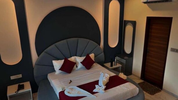 A modern bedroom with a curved bed, a ceiling fan, and an air conditioning unit. - Hotel Kamla Kishan (Khatoo)