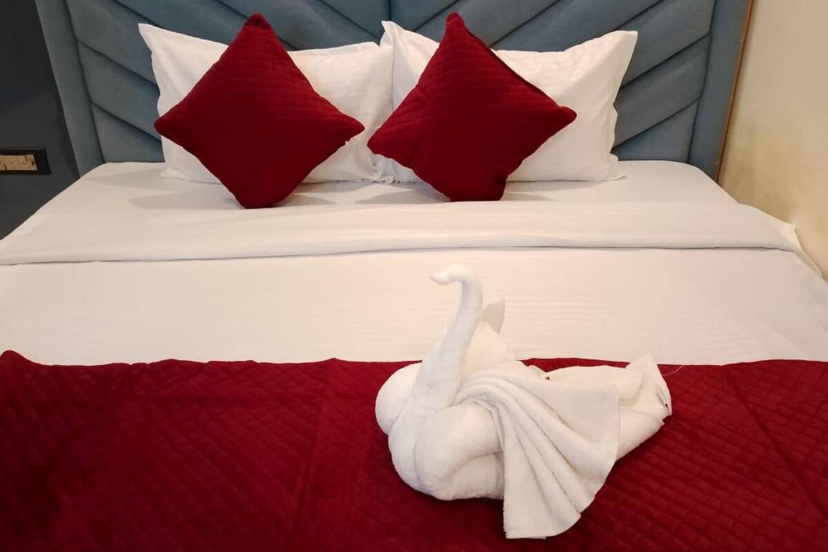 Ein Bett mit blauem, gepolsterten Kopfteil, weißer Bettwäsche und zwei roten Kissen.