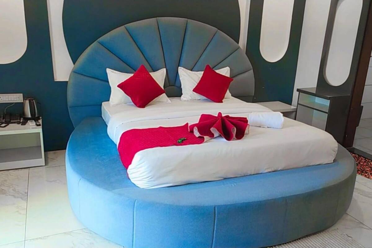 Ein Bett mit blauer Polsterkopfteil, weißer Bettwäsche und roten Kissen.
