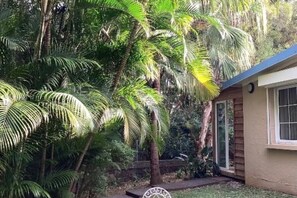 Uma casa com jardim, palmeiras e um pequeno pátio.