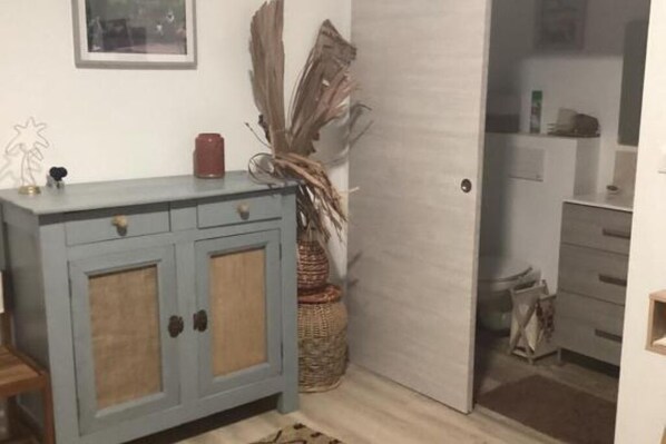 Um quarto com um armário azul claro com duas portas, uma cesta de vime e uma porta que dá para outro cômodo.