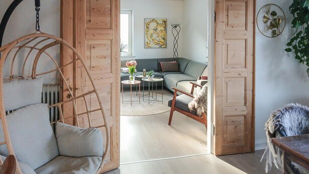 Una sala de estar acogedora con un sillón colgante, un sofá y una mesita con plantas.