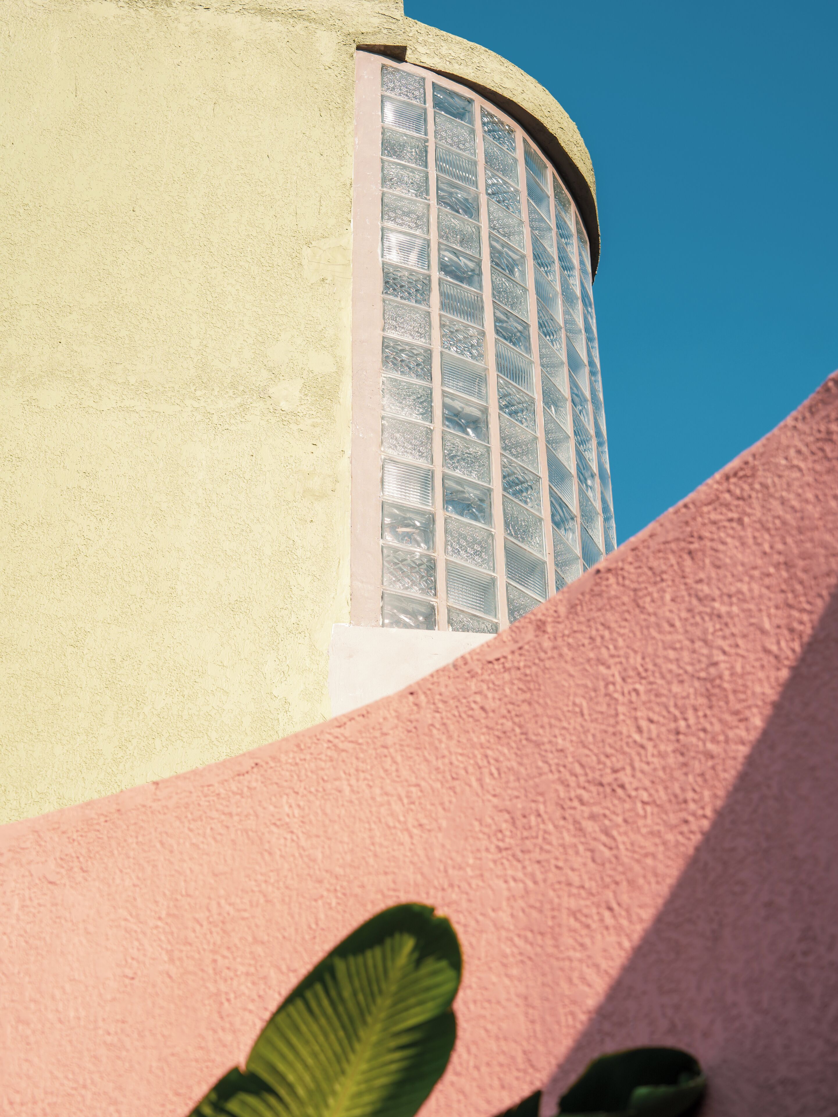 A building with a curved facade, a window with a grid pattern, and a clear blue sky.