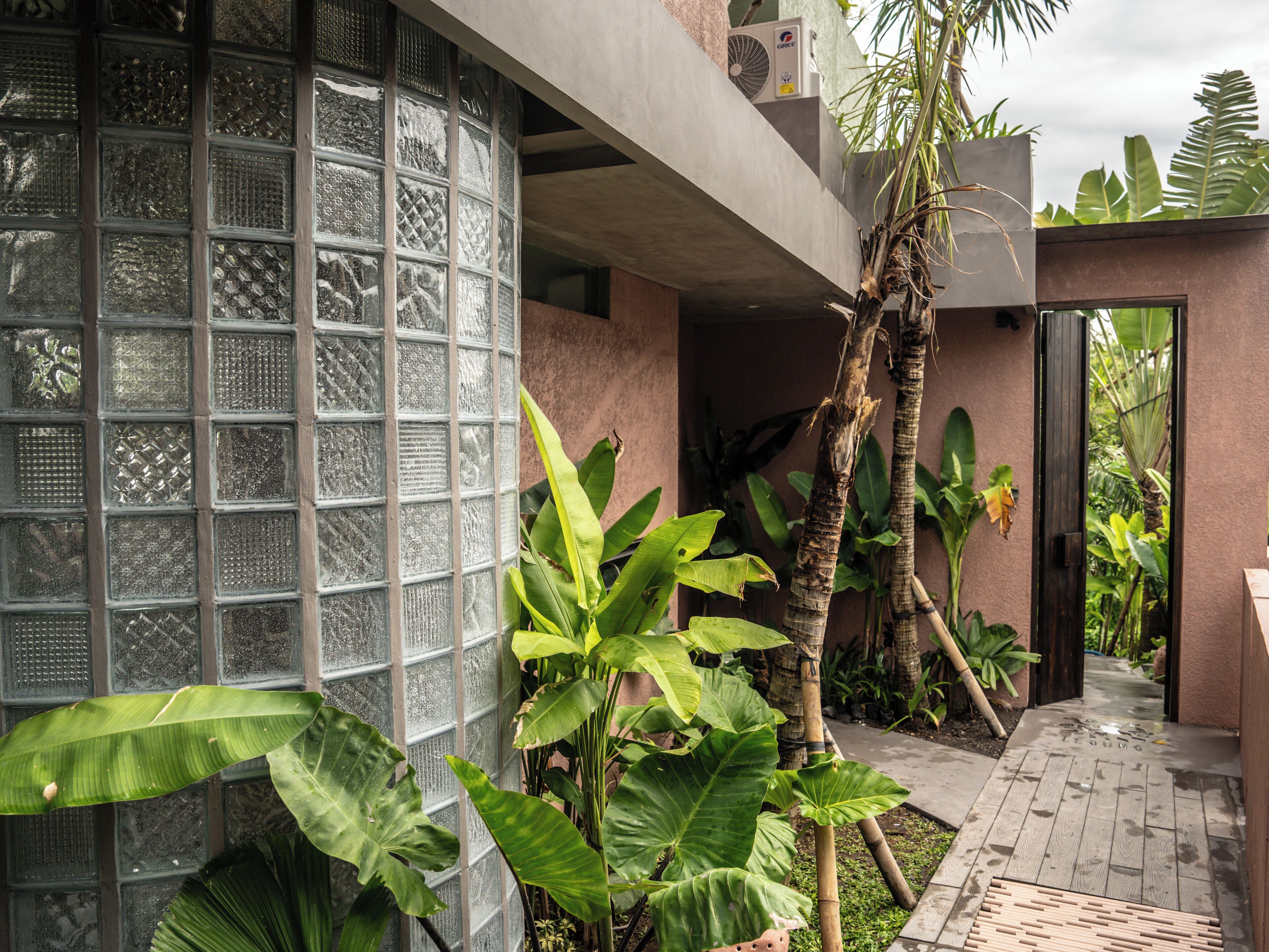 A modern building with a glass facade, a concrete exterior, and a pathway leading to a door.