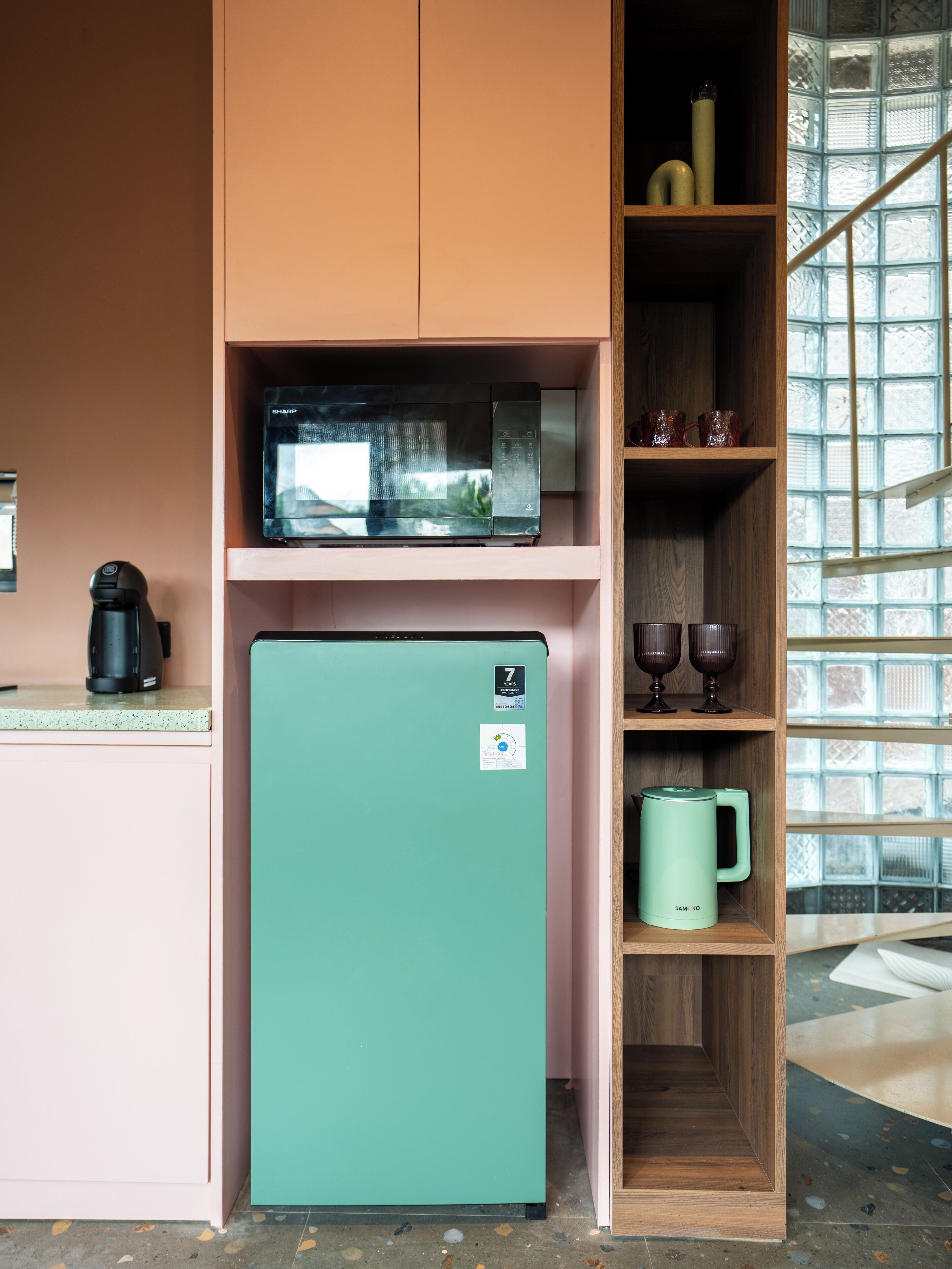 A compact kitchen with a teal refrigerator, a microwave, and a coffee maker on the countertop.