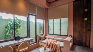 A modern room with a large window, a sofa, a desk, and a chair. - Patha (Canggu)