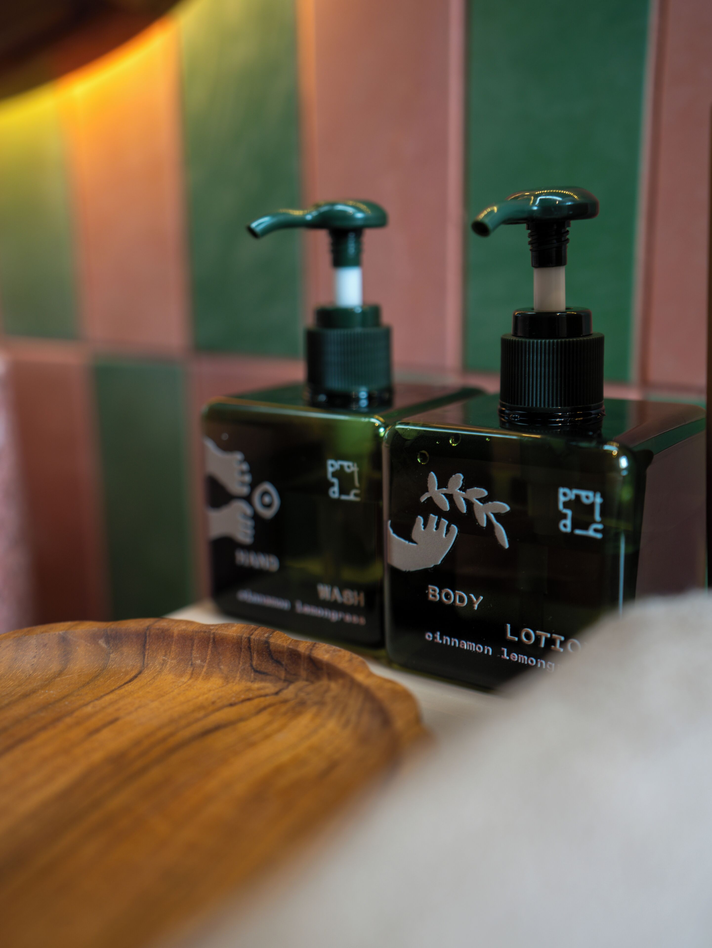 Two bottles of body lotion with pump dispensers on a wooden surface.