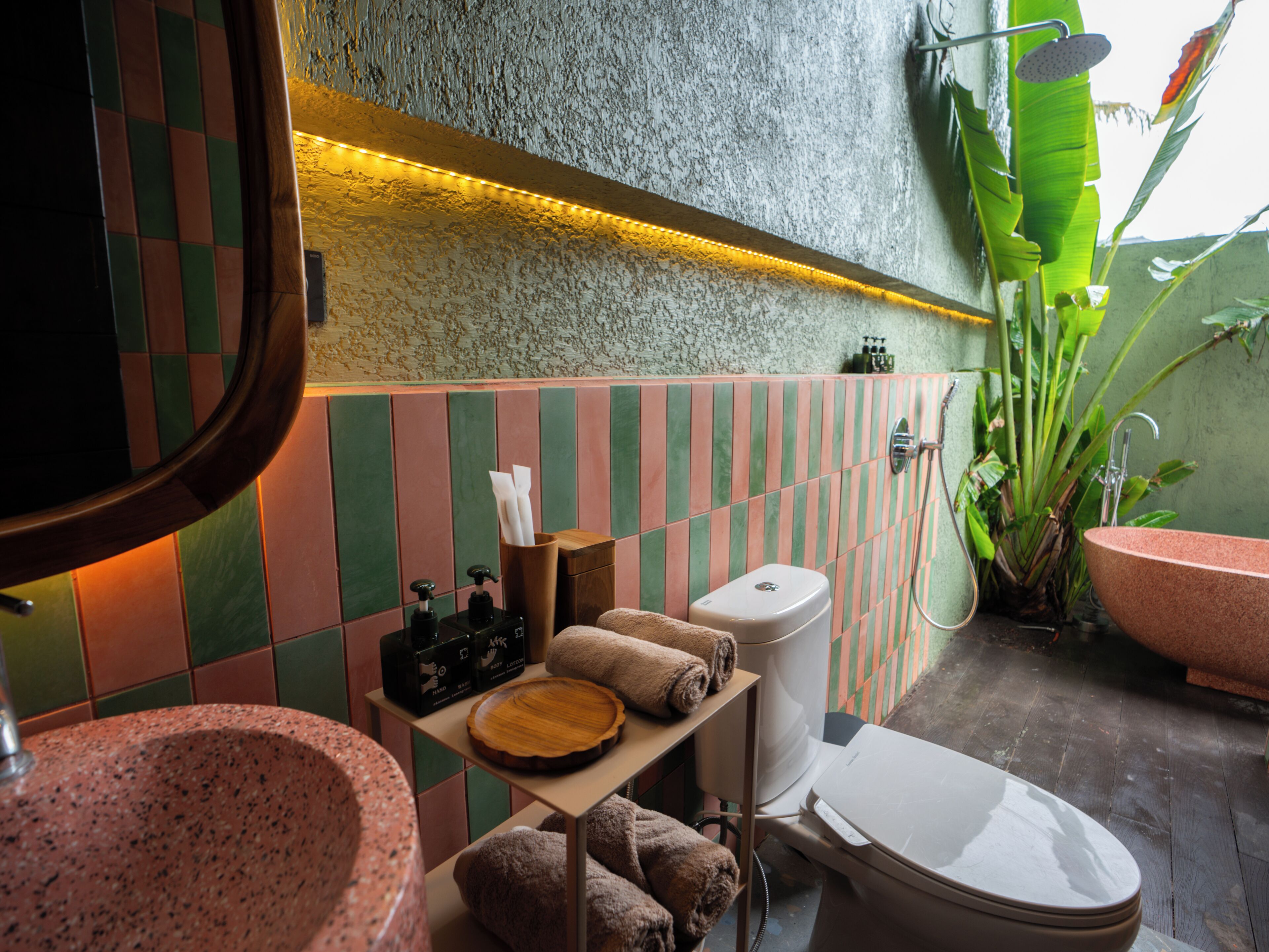 Une salle de bain avec un lavabo, des toilettes et une douche. Des serviettes et des articles de toilette sont posés sur une étagère.