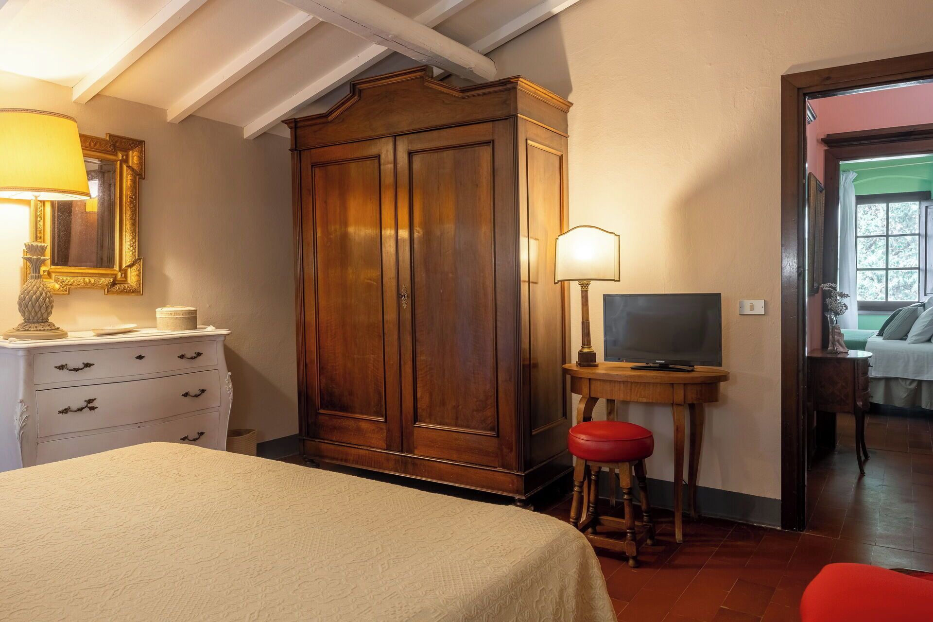 A bedroom with a bed, a wardrobe, a television, and a lamp.