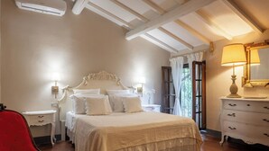 Un dormitorio con cama, mesitas de noche, una silla, cómoda y una ventana con cortinas.