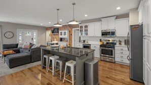Una cocina moderna con armarios blancos, electrodomésticos de acero inoxidable y una isla central con taburetes de bar.