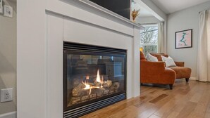 Una sala de estar moderna con chimenea, piso de madera y un sofá con cojines.