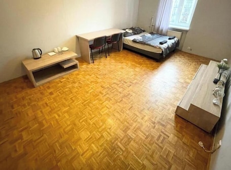 A compact room with a bed, a desk, and a small seating area.