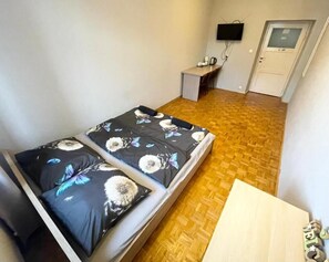 A small room with a bed, a desk, a television, and a door. - Fantastic Inn Warsaw - Górskiego (Warsaw)