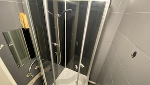 A glass-enclosed shower stall with a white sink and a handheld showerhead. - Fantastic Inn Warsaw - Górskiego (Warsaw)