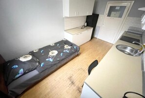 A compact room with a bed, a small kitchenette, and a door leading to a bathroom. - Fantastic Inn Warsaw - Górskiego (Warsaw)