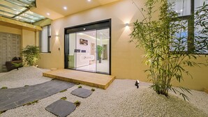 Ein modernes Gebäude mit Glastür, einer Holzdielen-Terrasse und einem Kiesweg, der zur Tür führt.