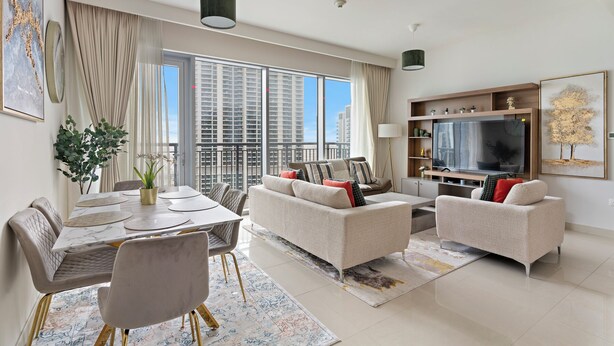 A modern living room with a dining area, large windows, and a flat-screen TV. - Elegant 1BR with Panoramic Views (Dubai)