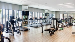 A modern gym with treadmills, elliptical machines, and weightlifting equipment. - Elegant 1BR with Panoramic Views (Dubai)