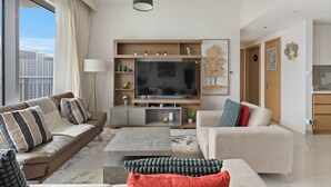 A modern living room with a large flat-screen TV, two sofas, a coffee table, and a dining area. - Elegant 1BR with Panoramic Views (Dubai)