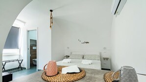 A modern bedroom with a bed, bedside tables, and a view of the bathroom. - Tresor 39 - Blanco (Polignano a Mare)