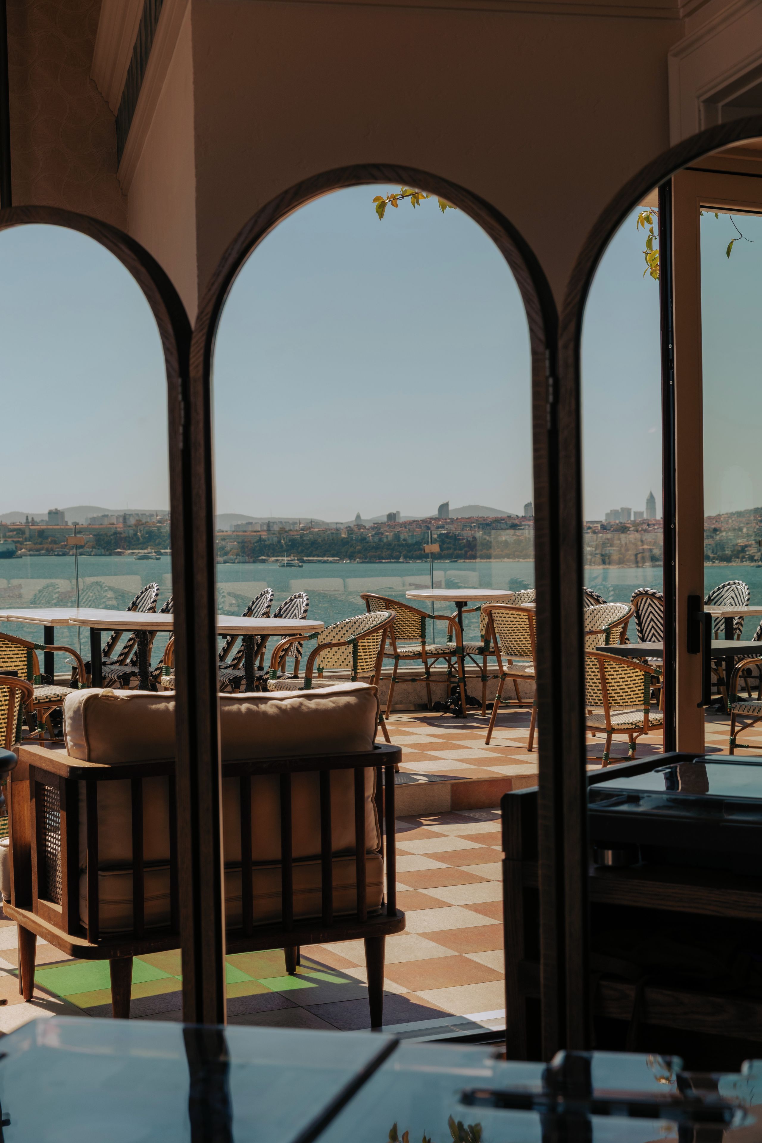 A terrace with wicker furniture and a view of a cityscape.