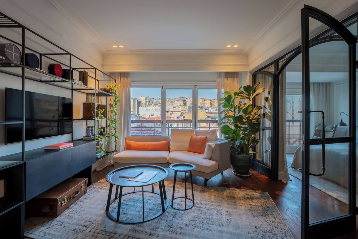 A modern living room with a sofa, two side tables, a TV, and a bookshelf.