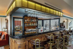 A bar area with a marble countertop, multiple stools, and a variety of bottles and glasses.