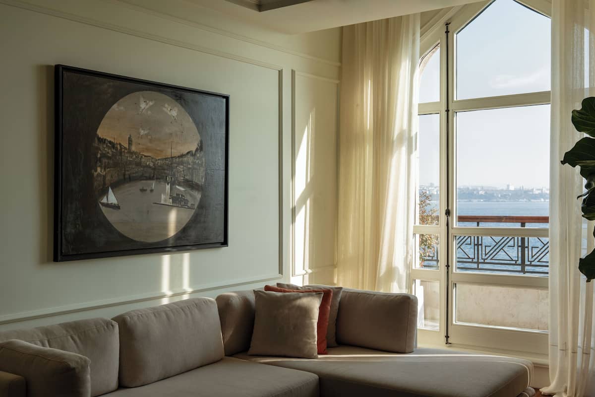 A living room with a large window, a sofa, and a painting.